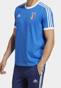 Blå bomullströja med vita detaljer, rund hals, och italiensk flagga logotyp på bröstet. Tre vita ränder på axlarna.