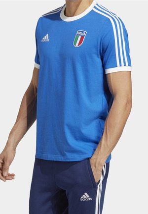 Niebieska bawełniana koszulka z białymi akcentami, okrągły dekolt oraz logo włoskiej flagi na piersi. Trzy białe paski na ramionach.