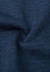 Mörkblått stickat tyg med en slät, något strukturerad yta, som visar fina stygn och en enhetlig färg genom hela tyget.