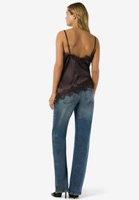 Pruuni satiinist kampsun pitsilise äärega, reguleeritavate spagetirihmadega, koos tuhmiks kulunud siniste sirge laiusega teksade ja mustade kontsakingadega.