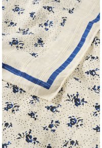 Lengvas audinys su mažais mėlynais gėlių raštais ir juodais taškeliais, puoštas vientisos mėlynos spalvos stačiakampio formos rėmeliu.