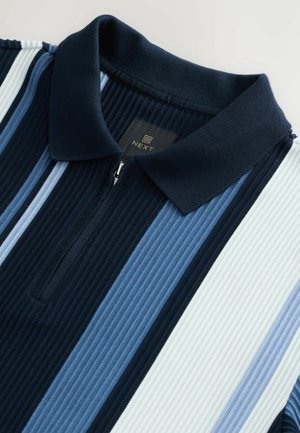 Polo cu dungi verticale în navy, albastru deschis și alb. Guler cu fermoar și textură cu model în relief. Eticheta cu logo-ul "NEXT" este vizibilă.
