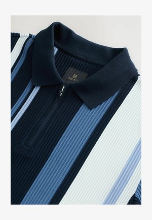 Sötétkék, világoskék és fehér függőleges csíkos póló. Cipzáros gallér ribbelt textúrával. "NEXT" logós címke látható.