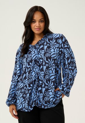 Navy blue long-sleeve shirt with a floral pattern in light blue. Features a buttoned front and a rounded hem. Made of textured fabric.