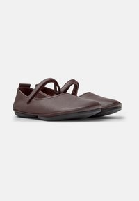 Brown leather shoes with a soft texture, pointed toe design, and two crisscross straps. Features a flexible black rubber sole.