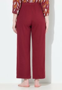 Bordeaux katoenen broek met een ontspannen pasvorm, elastische tailleband en recht gesneden pijpen. Soepele textuur, afgewerkte zomen en geen zakken.