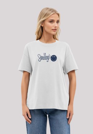 White cotton t-shirt featuring a navy blue "Smiley" logo and smiley face graphic. Designed with short sleeves and a relaxed fit.