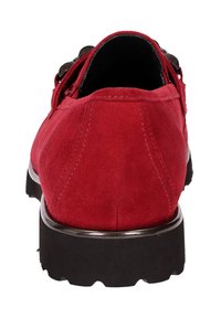 Rode suède schoen met een ronde neus, platte zwarte rubberen zool en decoratieve hardware aan de zijkant. Toont stiksels aan de hiel.