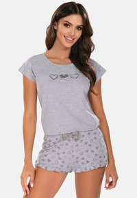 Grijze katoenen pyjama set met een kortemouwen top met hartjesprints en grijze shorts versierd met hartenpatronen en een strik op de tailleband.