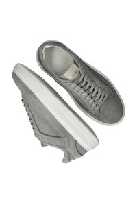 Grijze suède sneakers met witte rubberen zolen. Kenmerkend zijn de zachte, ronde neus, zes grijze veterogen en een textuurontwerp aan de zijkant.