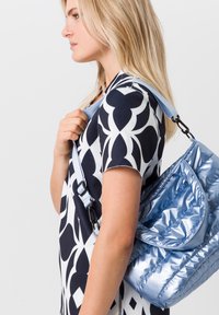 Sac à main matelassé bleu clair avec un design incurvé, fermeture éclair et bandoulière ajustable. Le sac présente une texture brillante et une silhouette douce.