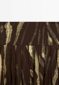 Bruine stof met lichtbeige abstracte patronen, voorzien van plooien en een gladde textuur. Het ontwerp heeft een natuurlijke, vloeiende uitstraling.