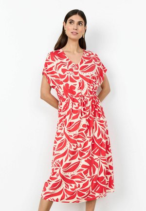 Ženska, oblečena v rdečo in belo obleko z rožnatim vzorcem do kolen, s kratkimi rokavi, v-izrezom in poudarjenim pasom.