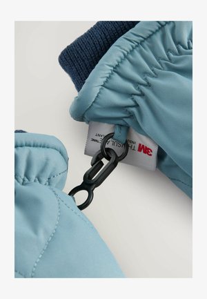 Svijetloplava izolirana rukavica s debelim tamnoplavim pletivom, opremljena crnim kopčom i oznakom za njegu pričvršćenom unutra.