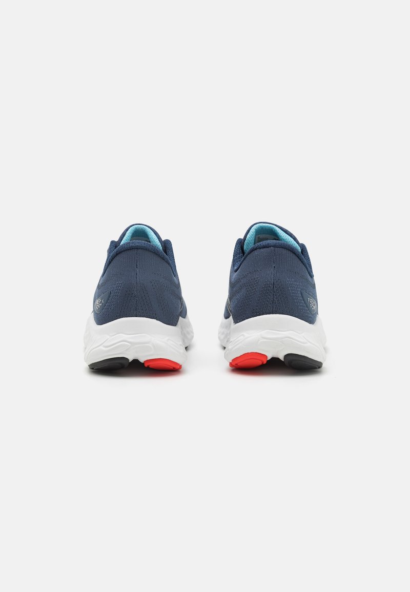Blaue textile Sport Schuhe mit weißen Sohlen, verfügen über einen gepolsterten Fersenkrause und Akzente in Rot und Schwarz an der Sohle.