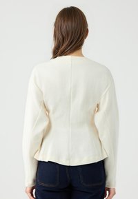 Cremfarbener, taillierter Pullover aus weichem Strickmaterial, mit Rundhalsausschnitt, langen Ärmeln und einem Peplum-Saum.