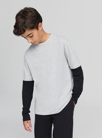 Maglietta grigia a maniche corte con maniche lunghe nere, realizzata in tessuto morbido. La maglietta ha una vestibilità comoda e un orlo arrotondato per il massimo comfort.