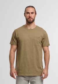 Khaki kortärmad t-shirt gjord av mjukt tyg. Har en bröstficka med en färgad detalj. Rundad halsringning och avslappad passform.