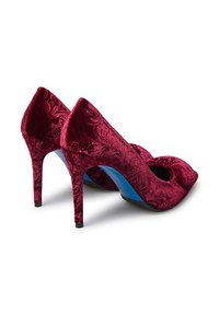 Red velvet high-heeled shoes with floral texture, pointed toe, cut-out detail, and a blue insole. Black heel adds contrast to the design.