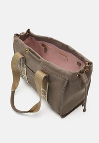 Bruine leren tote bag met een zachte textuur, roze interieur, gouden hardware en canvas schouderbanden met een logo patroon. Met een ritsvak aan de binnenkant.