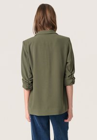 Olivově zelený blejzr s klopeným límcem a ohrnutými rukávy. Vyrobený z hladké tkaniny, má volný střih a jednoduchý design.