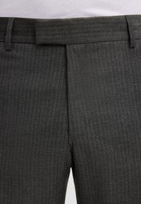 Primissimo piano di pantaloni grigi scuri con un sottile motivo a quadri e una vita con passanti per cintura.