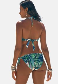 Bikini komplekts ar tropu lapu rakstu zaļā un zilā krāsā. Haltera kakla un saistāmās sānu biksītes. Gluda virsma, minimālistiski aksesuāri.