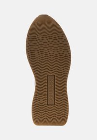 Suola in gomma marrone con una trama ondulata e la parola "GUESS" impressa al centro. Il design è incentrato sulla trazione e sulla durata.
