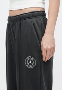 Ciemnoszare dresy z elastycznym paskiem, z okrągłym logo z białym haftem "PARIS" i "SAINT-GERMAIN".