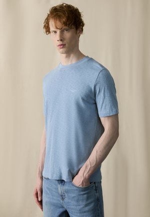 Ljust blå t-shirt i mjukt tyg, med en klassisk rund halsringning och korta ärmar, tillsammans med blekta blå jeans.