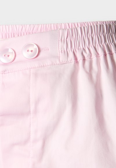 Ceinture de pantalon rose clair avec dos élastique et deux boutons blancs à l'avant pour un ajustement et une fermeture réglables.
