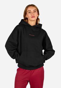 Čierna mikina s kapucňou a predným vreckom, s malým červeným logom "PEGADOR". Mäkkučký materiál s voľným strihom a rebrovanými manžetami.