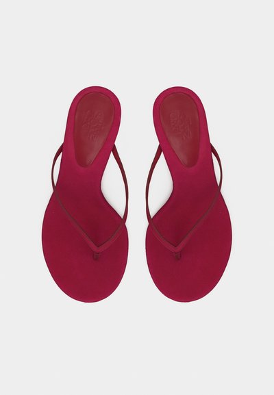 Ζευγάρι επίπεδων, κόκκινων παντόφλων με λεπτά λουριά και στρογγυλεμένη σόλα, απεικονισμένα από πάνω σε λευκό φόντο.