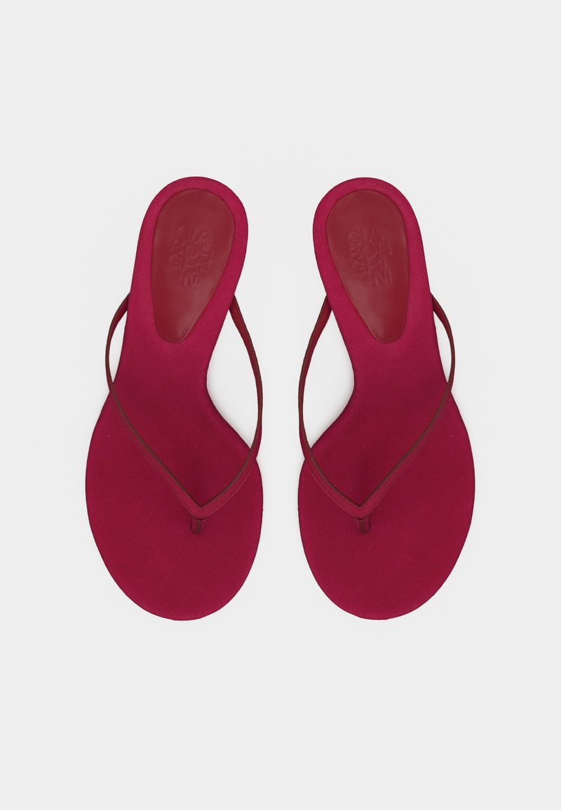 Paire de chaussons plats rouges avec des lanières fines et une semelle arrondie, vue de dessus sur un fond blanc.