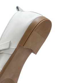 Scarpa in pelle bianca con suola in gomma leggera marrone chiaro testurizzata, dotata di una fascia decorativa e un accento grigio sul tallone.