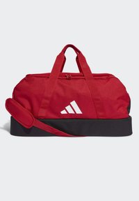 Bolso de viaje rojo con base negra, doble asa, correa ajustable y un detalle de logotipo blanco. Fabricado con tela duradera y cierre de cremallera.