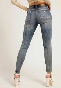Jeans ajustados en denim azul claro, con cintura alta, cinco bolsillos y un parche del logo en la parte trasera de la cinturilla. Tejido texturizado con un ligero desgaste.