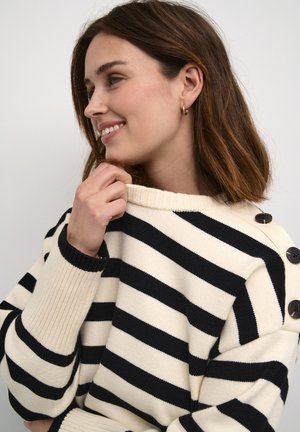 Striped sweater in cream and black, featuring ribbed cuffs and shoulder buttons. Soft texture, relaxed fit, wider neckline.