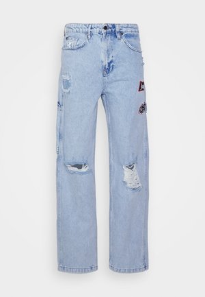 Světle modré džíny z denimu s odřenými detaily, na přední straně s nášivkami různých tvarů a barev, volný střih a rovné nohavice.