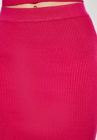 Figurbetontes, geripptes Midi-Rock in leuchtendem Fuchsia. Sanfte Textur mit breitem Bund; glatte Oberfläche ohne sichtbare Hardware oder Muster.