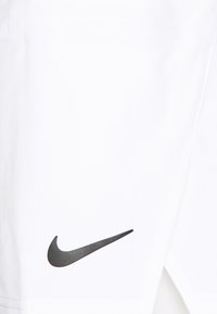 Weiße Baumwollshorts mit einem schwarzen Nike-Swoosh-Logo. Der Stoff ist glatt mit einem leicht glänzenden Finish, und der Schnitt zeichnet sich durch ein sauberes, maßgeschneidertes Design aus.