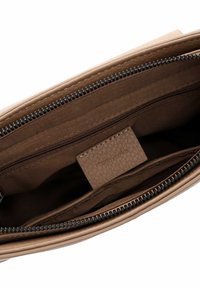 Interno di una borsa a tracolla in pelle beige che mostra più scomparti con zip e una fodera in tessuto marrone con etichetta del marchio Tamaris.