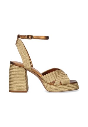 Sandalia de tacón alto y grueso con tiras beige trenzadas y plataforma, con una correa metálica en el tobillo con una pequeña hebilla.