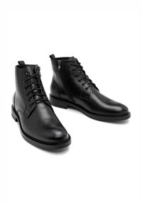 Czarne skórzane botki za kostkę z okrągłym noskiem, sznurowanym przodem, bocznym zamkiem błyskawicznym i teksturowaną podeszwą. Czysty, minimalistyczny design.