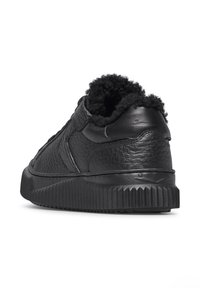 Sneaker in pelle nera con finitura testurizzata, rivestimento interno morbido e suola in gomma spessa e scanalata. Presenta dettagli di cucitura minimali.