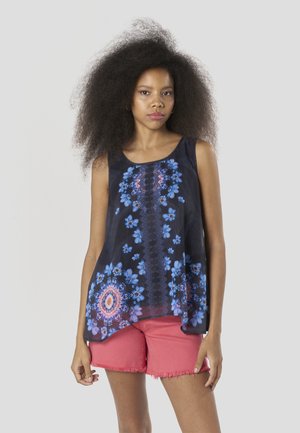 Sort ærmeløs top med blåt blomsterprint, med rund halsudskæring og et løstsiddende design. Matchet med lyserøde shorts med frynser.