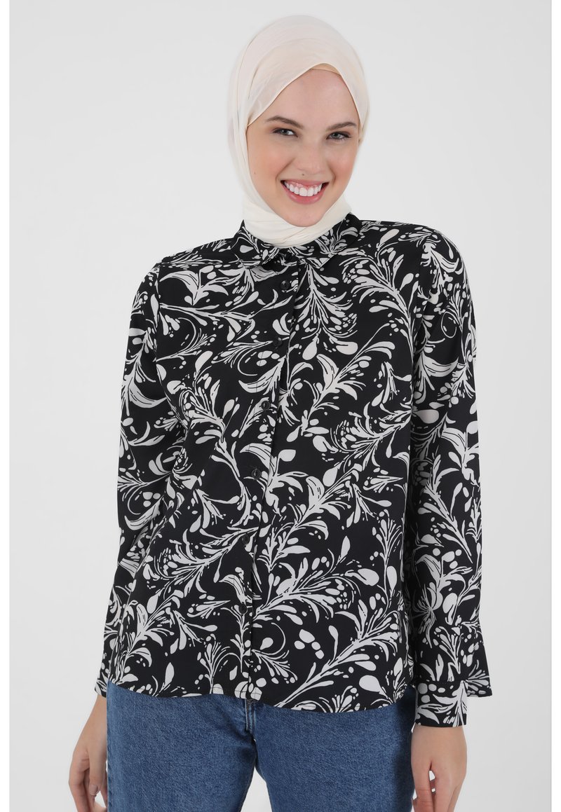 Black and white floral blouse with long sleeves, button closure, and a collared neckline. Fabrics feature a smooth, lightweight texture.