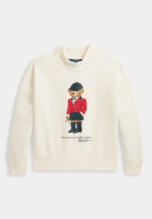 Kremowa bluza z Polo Bear w czerwonej kurtce, czarnym hełmie, butach i trzymająca bat jeździecki, z napisem Polo Bear by Ralph Lauren poniżej.