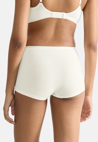 Elfenbensfarvet bomuldsboksershorts med en glat tekstur, midt-lav pasform og minimale syninger. Har en sømløs taljebånd for komfort og elasticitet.