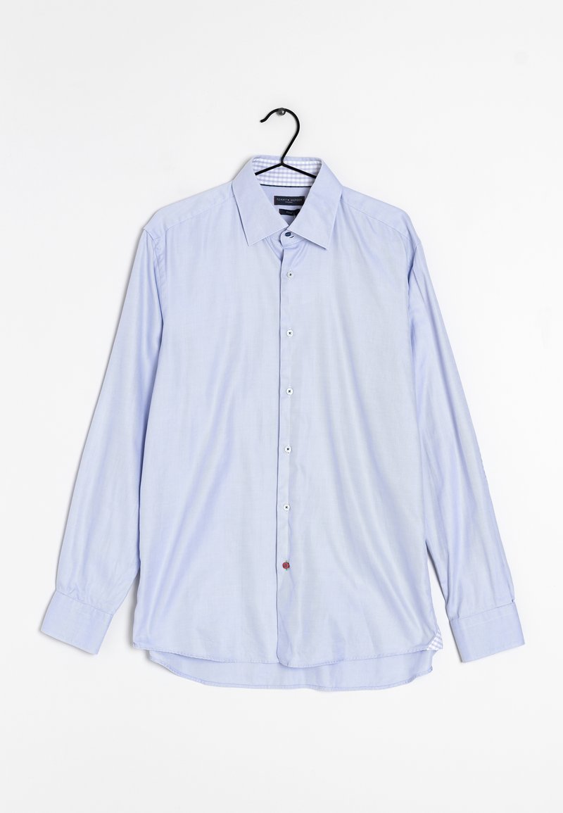 Chemise bleu clair à manches longues avec boutons, col et poignets, suspendue sur un cintre noir sur fond blanc.
